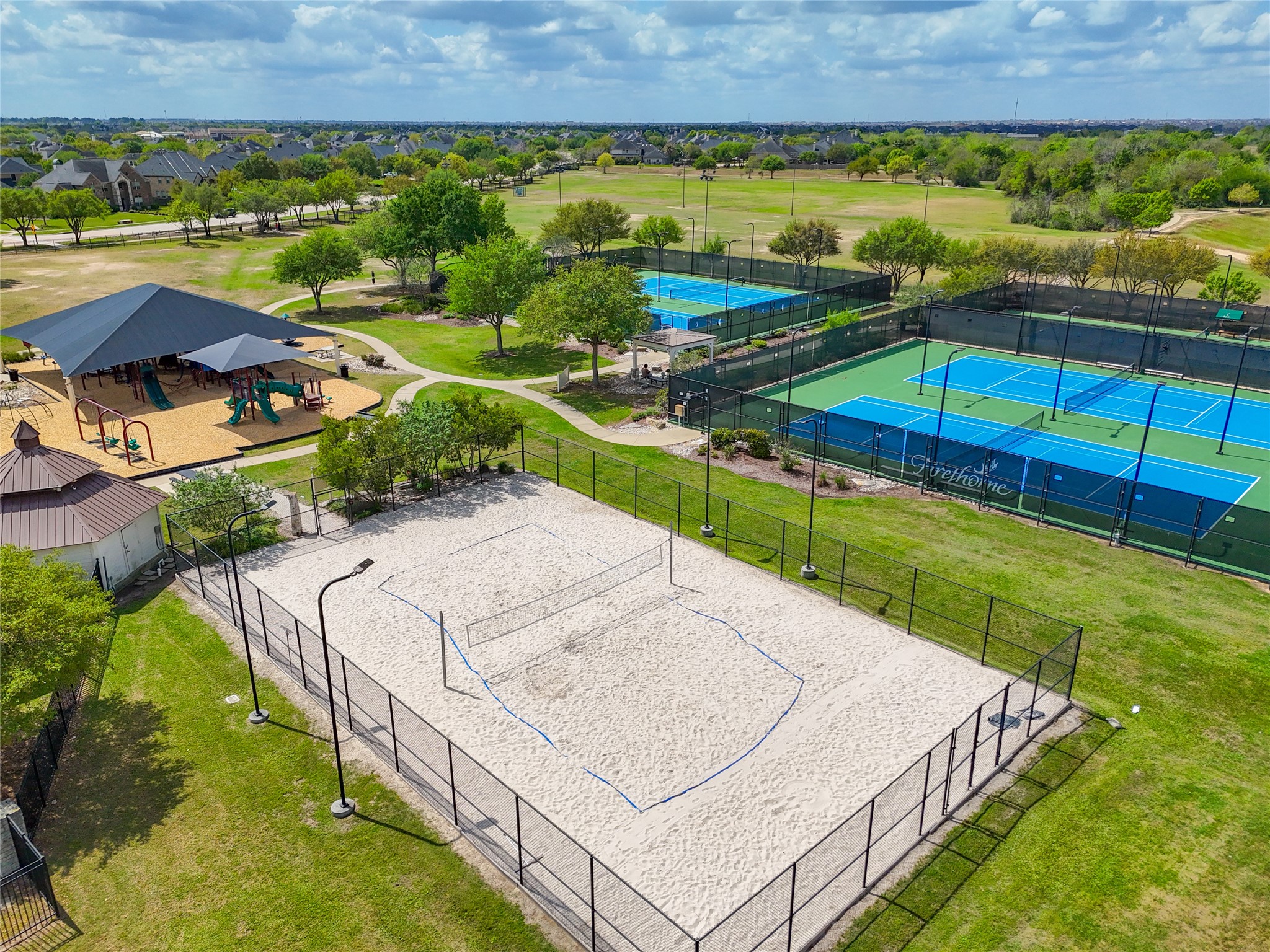 2818 Red Maple Drive Katy, TX 77494 - Photo 47 of 50 Firethrone Community recreational area with tennis courts, a sand volleyball court, and a shaded playground, all surrounded by green spaces and walking paths. Ideal for active family living.