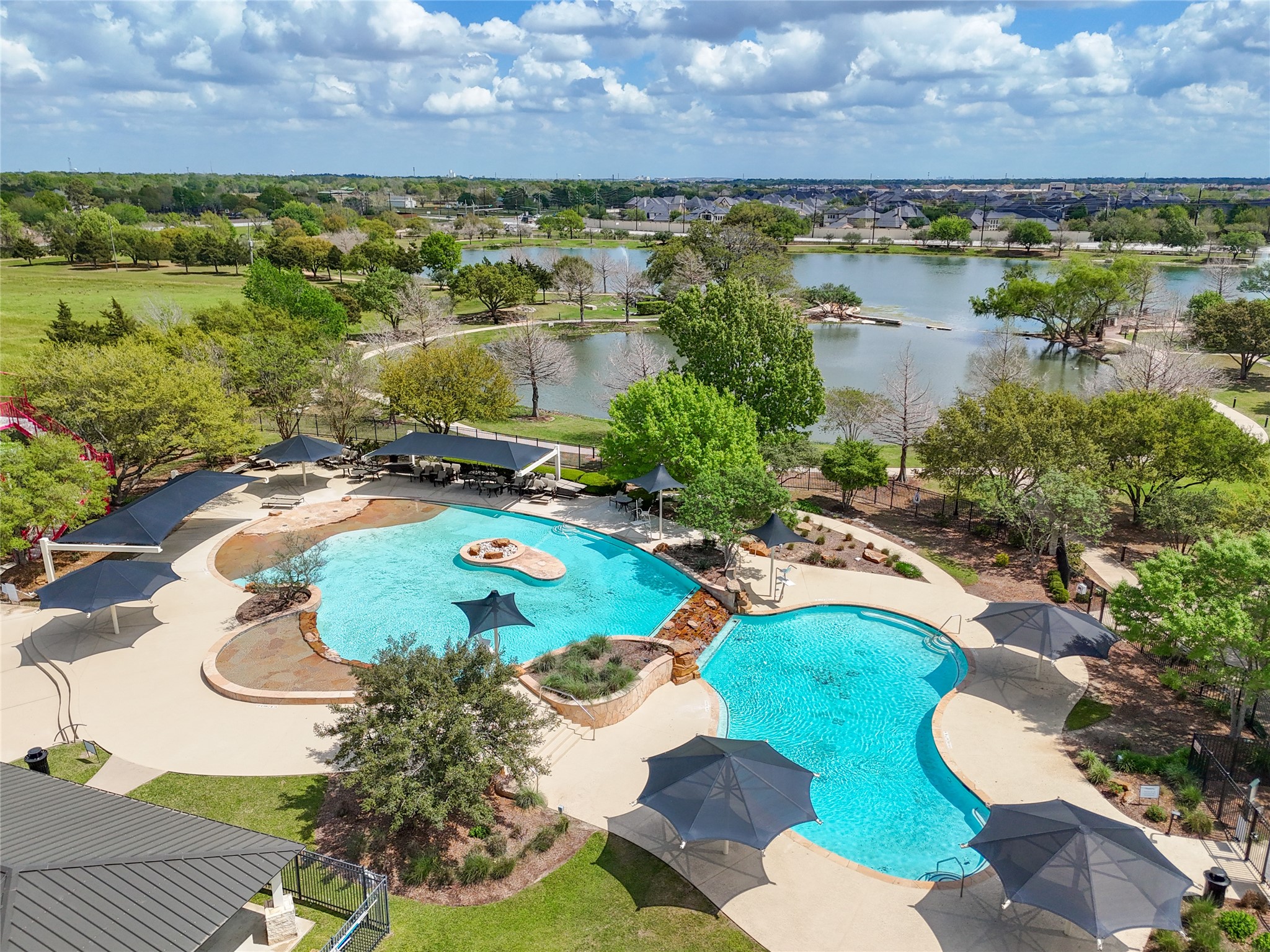 2818 Red Maple Drive Katy, TX 77494 - Photo 49 of 50 Firethrone has a beautifully landscaped community area featuring a large, resort-style pool with shaded seating areas. It's surrounded by lush greenery and overlooks a scenic lake, offering a tranquil and inviting setting for relaxation and recreation.