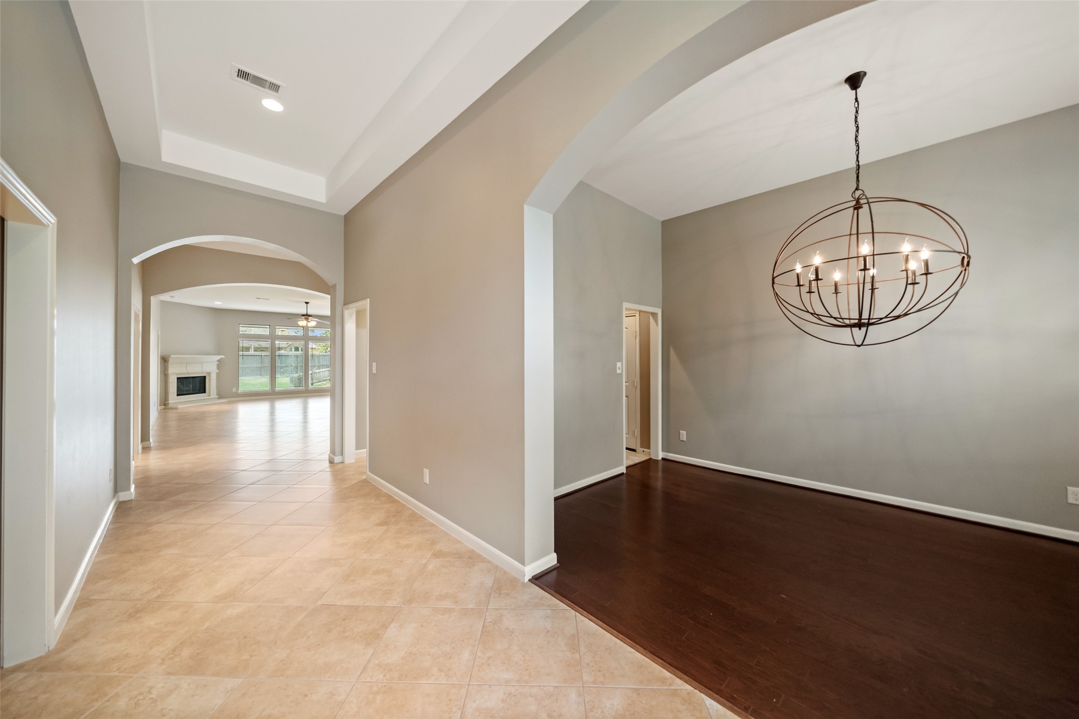 2818 Red Maple Drive Katy, TX 77494 - Photo 5 of 50 Spacious entryway with tile flooring leading into an open living area with a fireplace. Arched doorways and a modern chandelier add elegance, while large windows provide natural light.