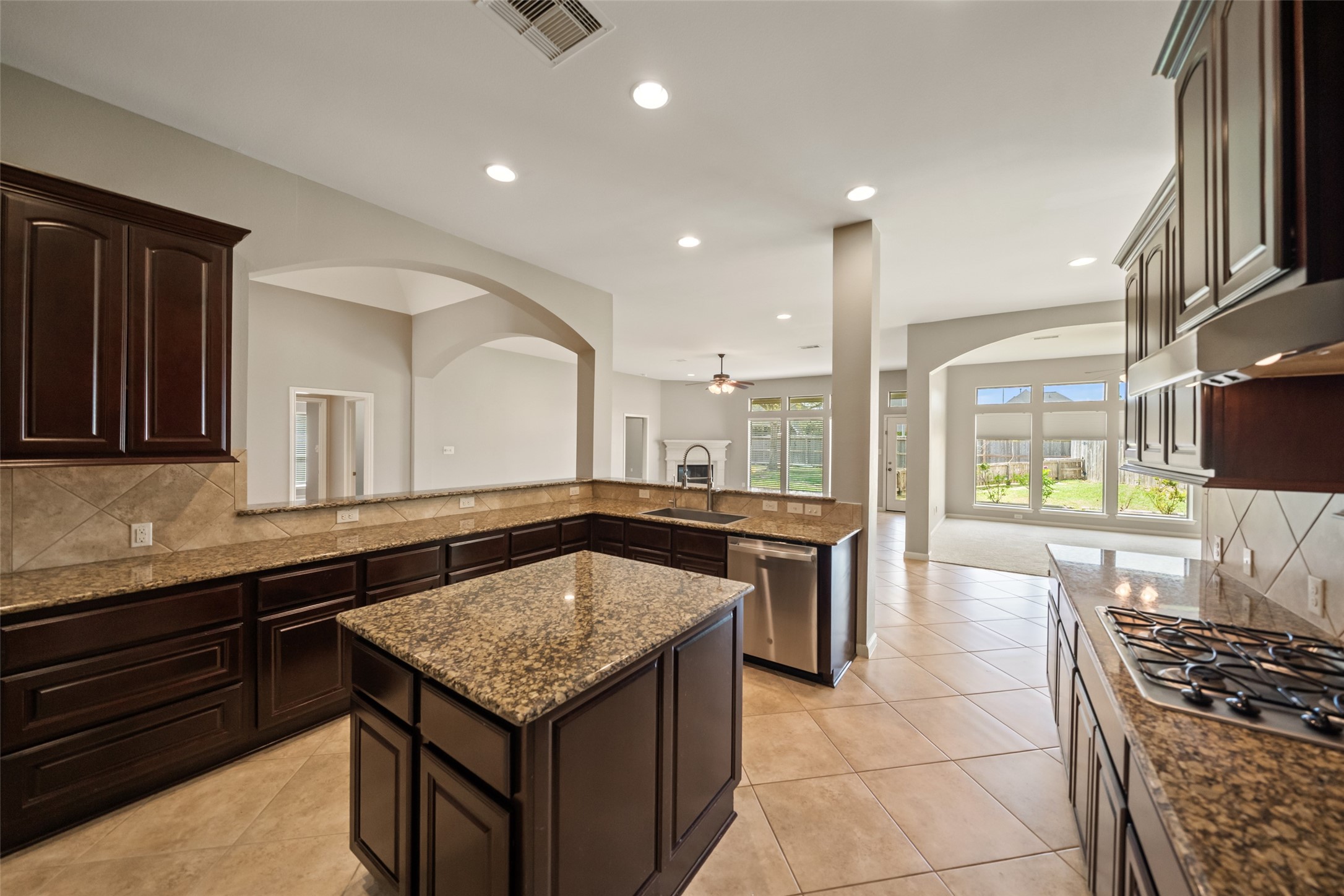 2818 Red Maple Drive Katy, TX 77494 - Photo 10 of 50 This spacious kitchen features elegant dark wood cabinets, granite countertops, and a large island. It opens to a bright living area with large windows and a view of the backyard, perfect for entertaining or family gatherings.