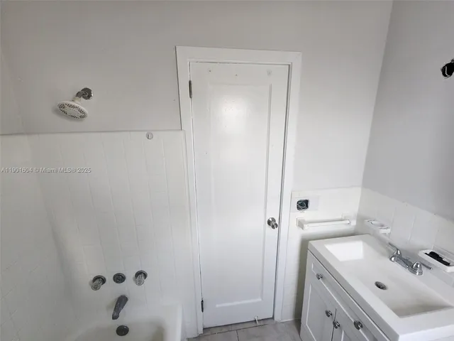 a bathroom with a tub sink vanity and mirror
