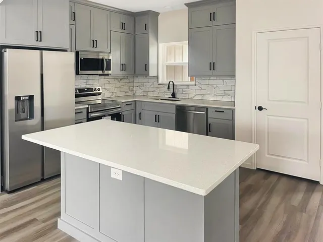 a kitchen with stainless steel appliances a white refrigerator a sink a stove a microwave and island