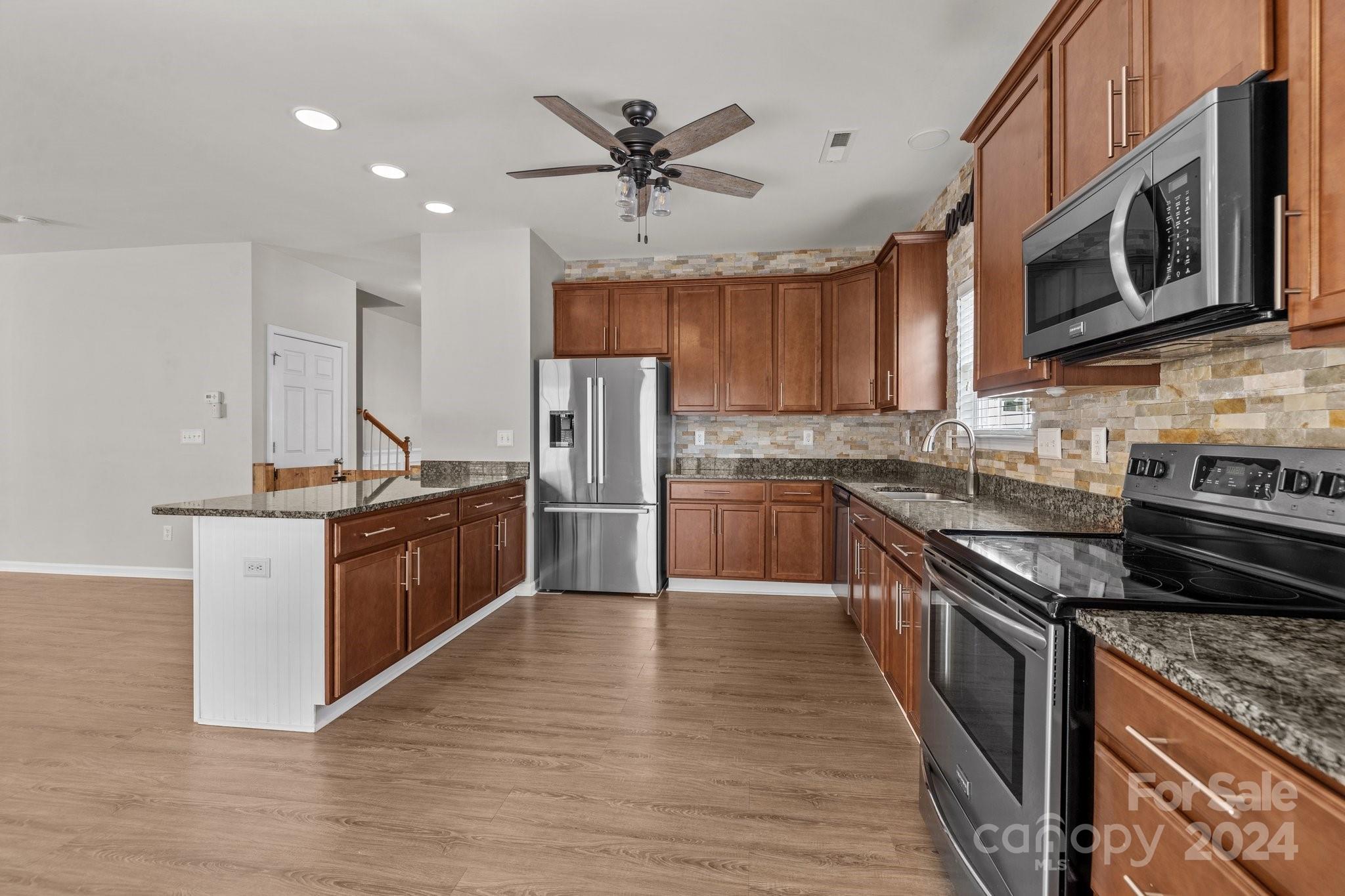 1653 Beleek Ridge Lane Clover, SC 29710 - Photo 12 of 46 a kitchen with stainless steel appliances granite countertop a stove top oven a sink dishwasher a refrigerator and cabinets with wooden floor