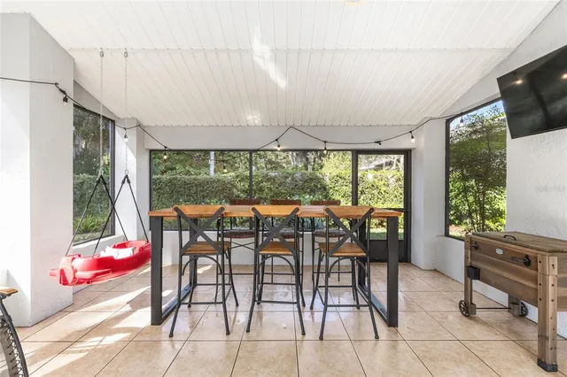 a view of a patio with table and chairs potted plants with floor to ceiling window