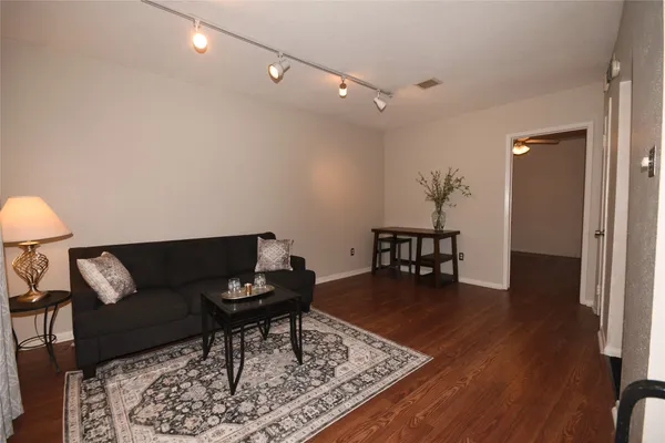 a living room with furniture and a dining table with wooden floor