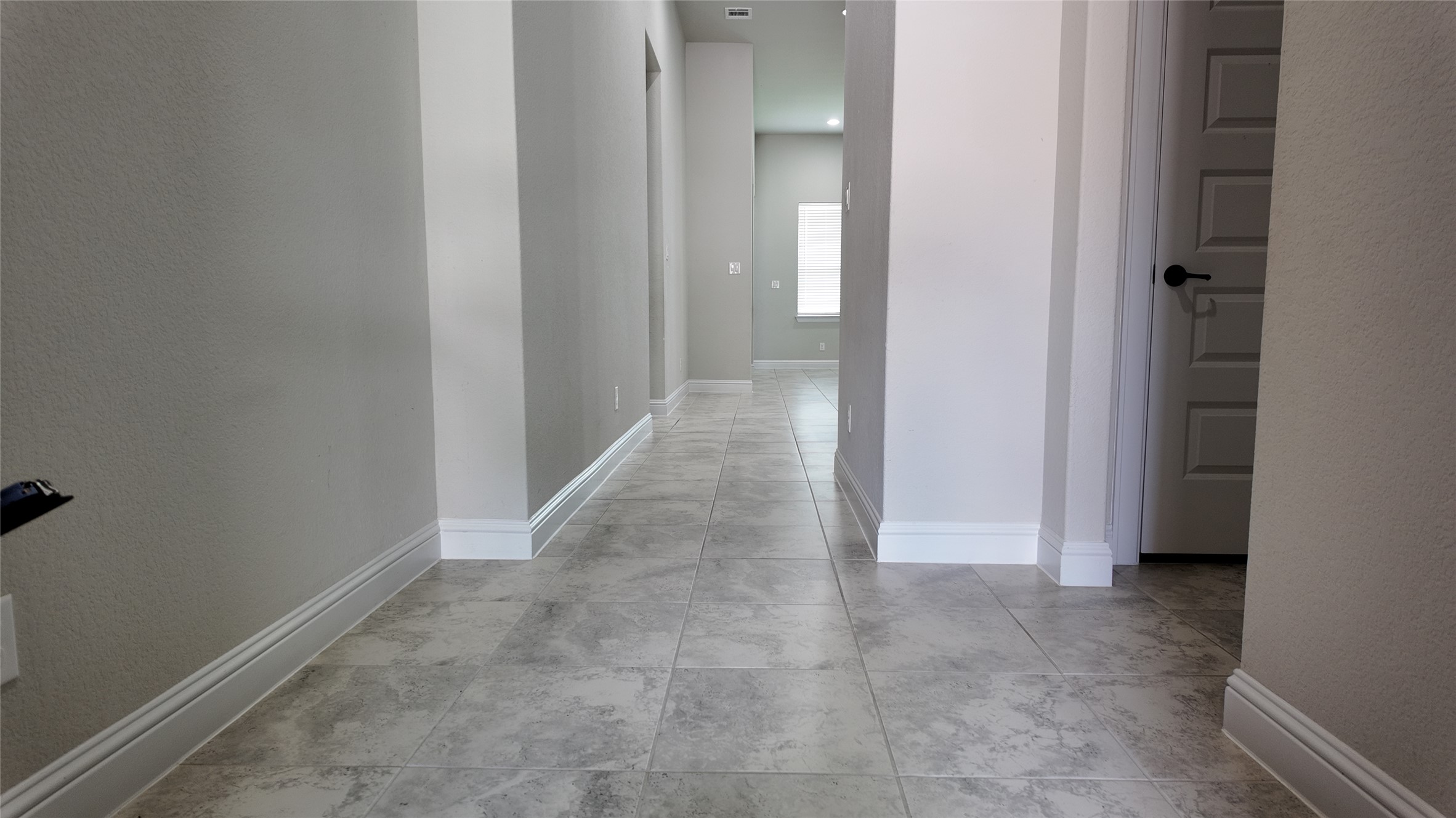 2320 Base Burner Path Leander, TX 78641 - Photo 3 of 24 A long corridor with contemporary tile flooring stretches through this modern home.