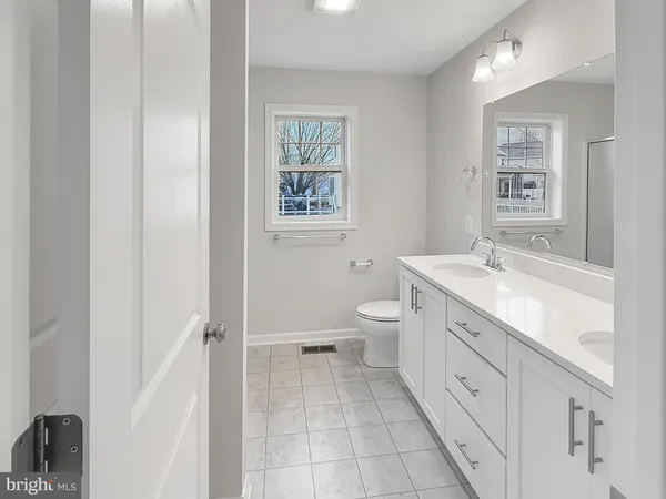 a spacious bathroom with a double vanity sink a mirror and a toilet