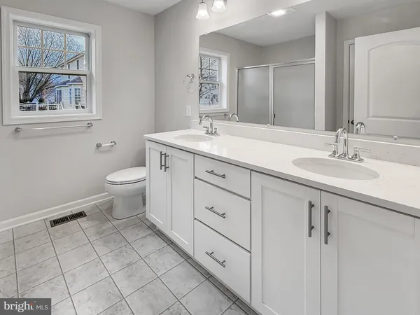 a spacious bathroom with a double vanity sink toilet and a mirror