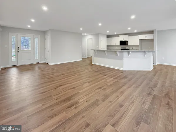 a view of kitchen with kitchen island wooden floor wooden cabinets and stainless steel appliances