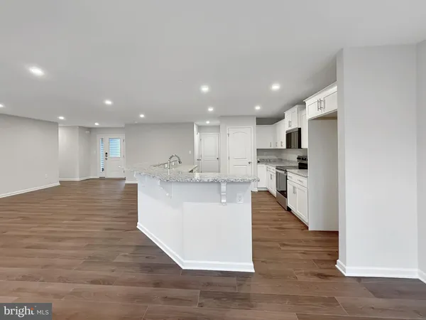 a view of kitchen with kitchen island stainless steel appliances refrigerator stove microwave and cabinets