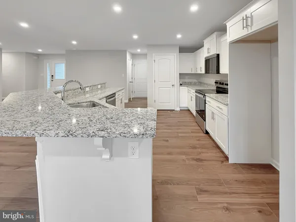 a kitchen with kitchen island granite countertop a stove top oven a sink and a refrigerator