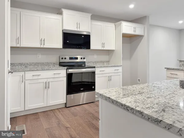 a kitchen with stainless steel appliances granite countertop a stove a sink and white cabinets