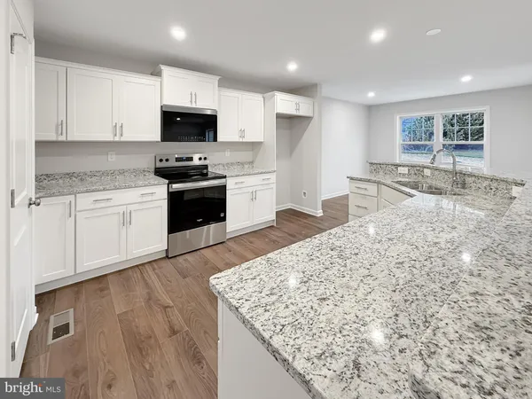 a large kitchen with cabinets appliances and a wooden floor