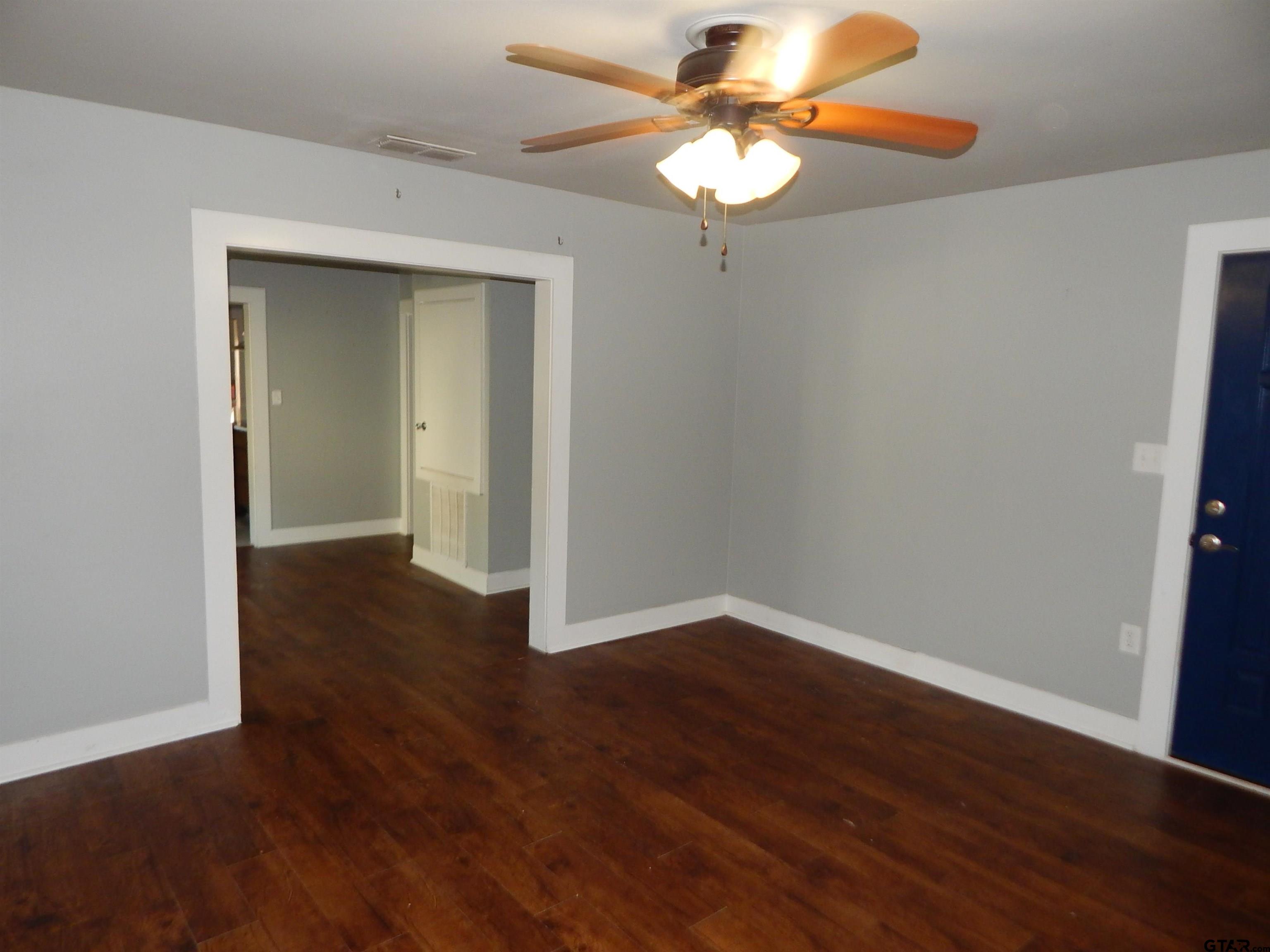 507 North Trinity Street Gilmer, TX 75644 - Photo 15 of 45 an empty room with wooden floor chandelier fan and closet area
