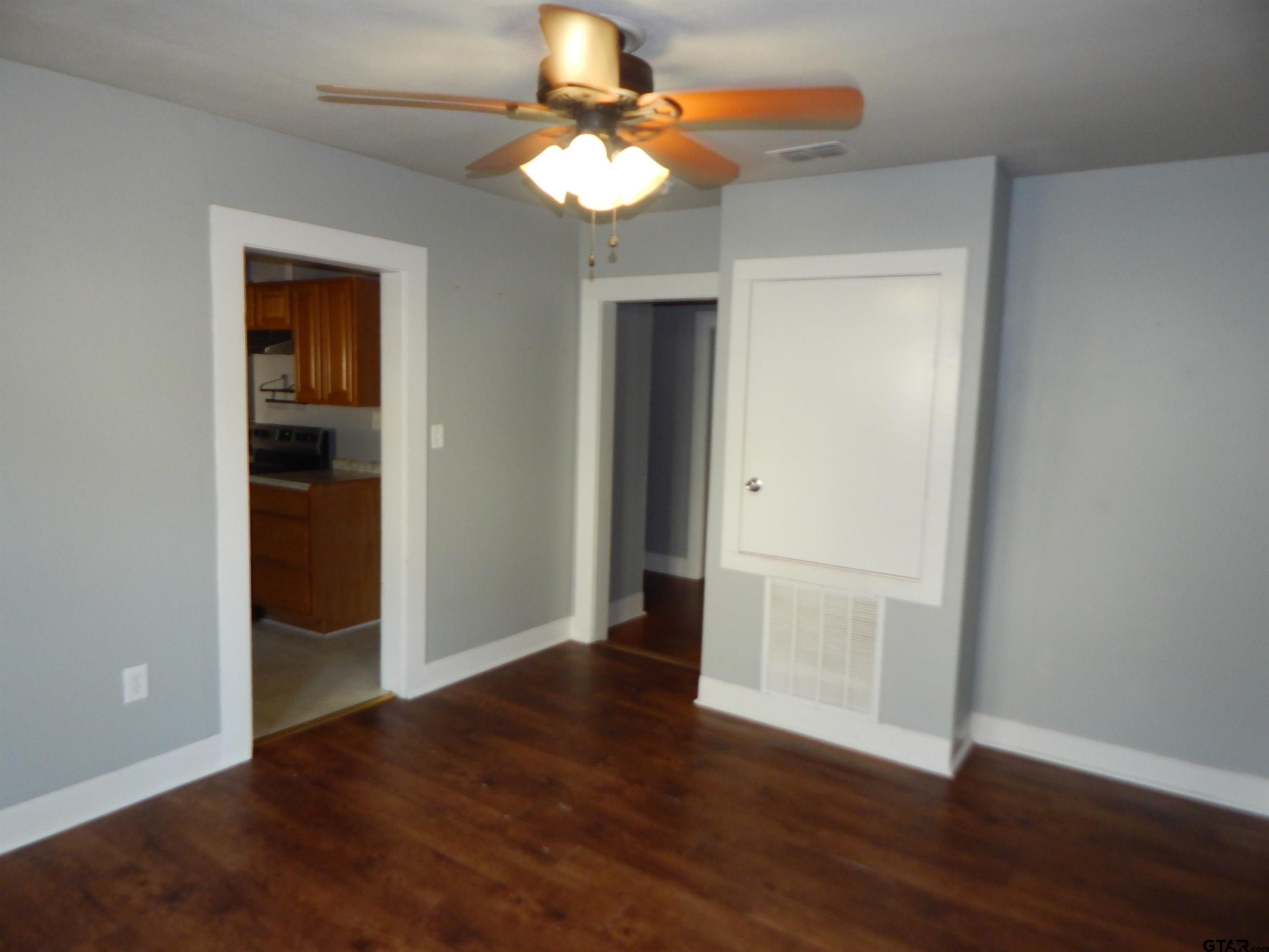 507 North Trinity Street Gilmer, TX 75644 - Photo 18 of 45 an empty room with wooden floor chandelier fan and closet