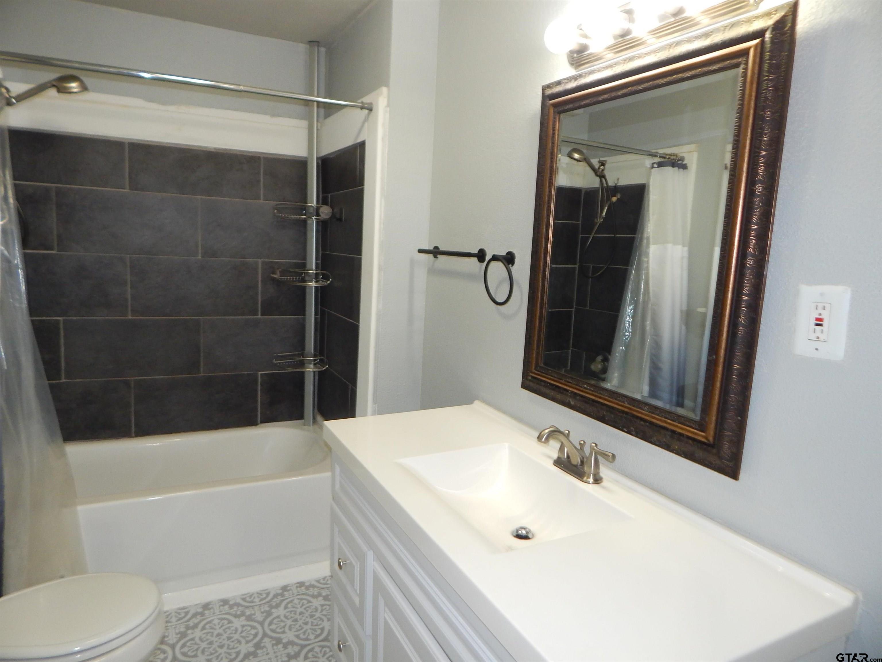 507 North Trinity Street Gilmer, TX 75644 - Photo 32 of 45 a bathroom with a tub a sink and a mirror