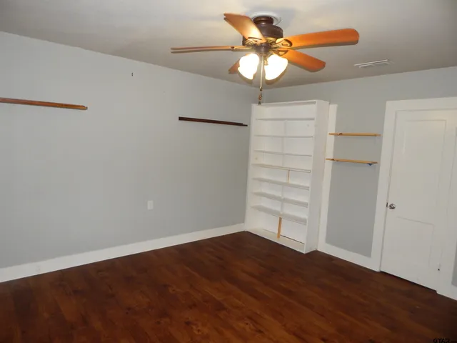 an empty room with wooden floor a chandelier fan and closet area
