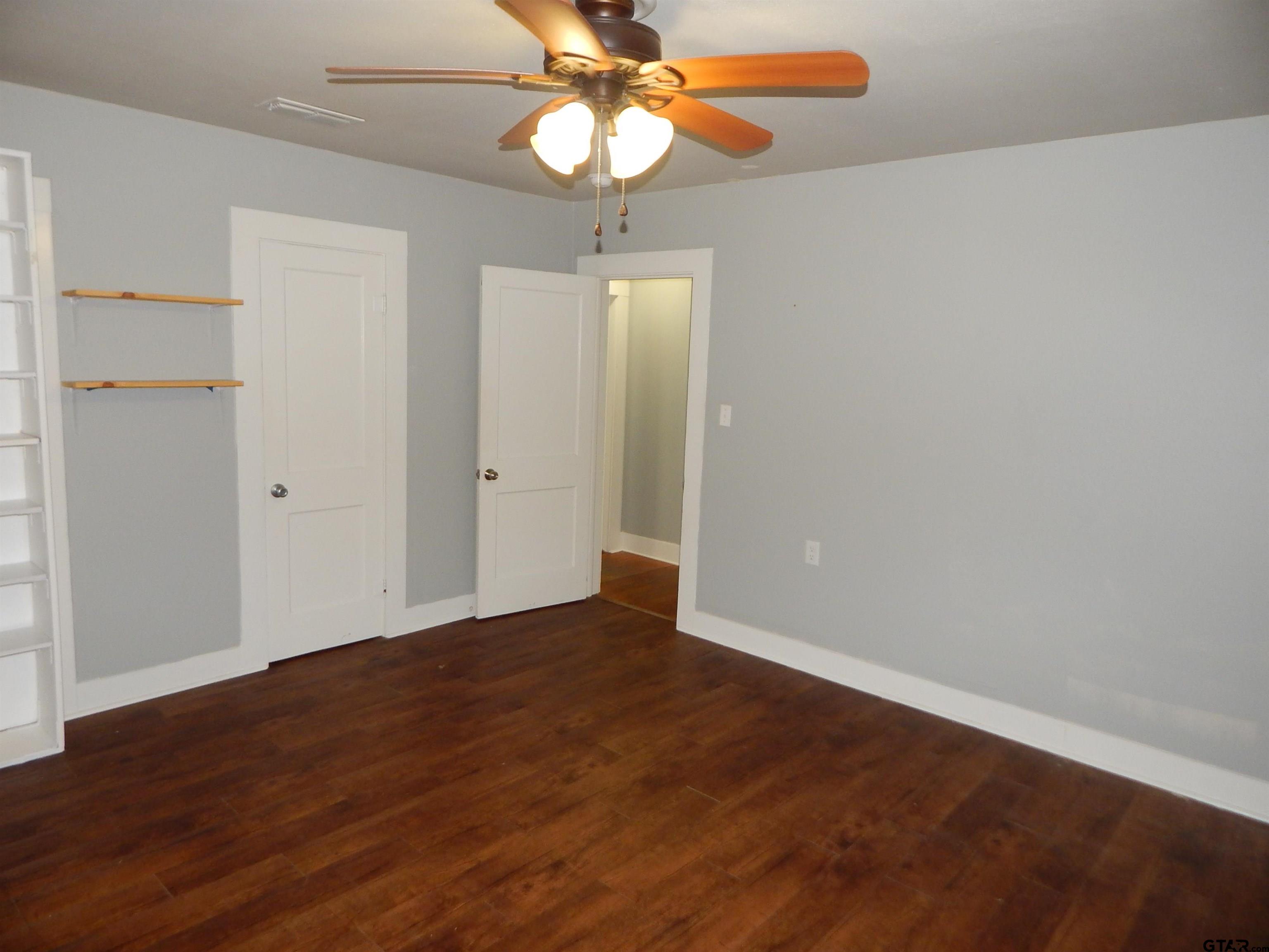 507 North Trinity Street Gilmer, TX 75644 - Photo 36 of 45 an empty room with wooden floor a chandelier fan and closet area