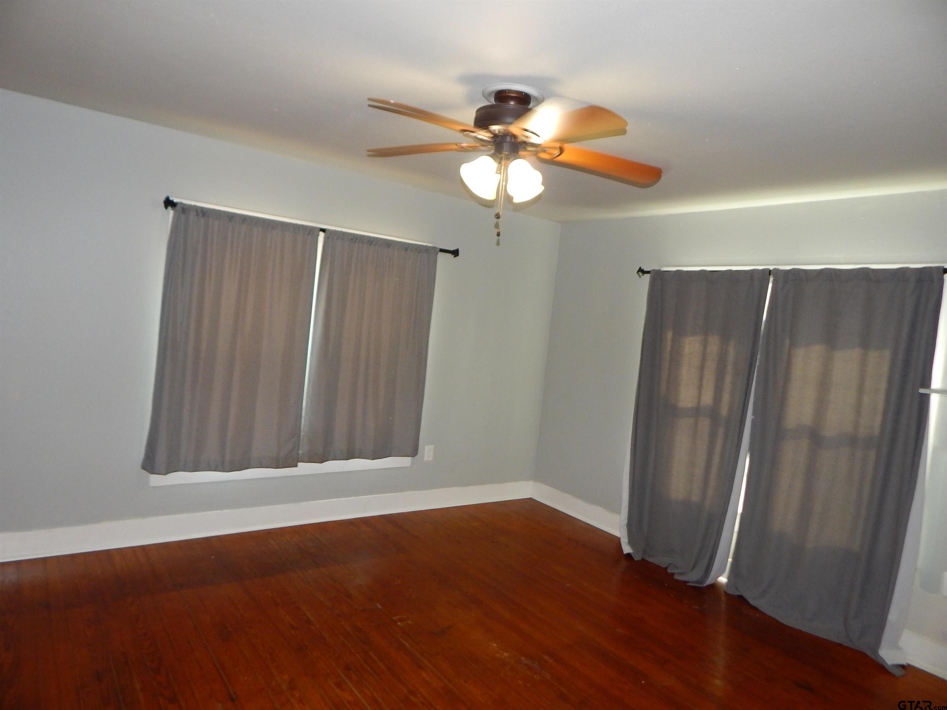 507 North Trinity Street Gilmer, TX 75644 - Photo 38 of 45 an empty room with wooden floor fan and windows