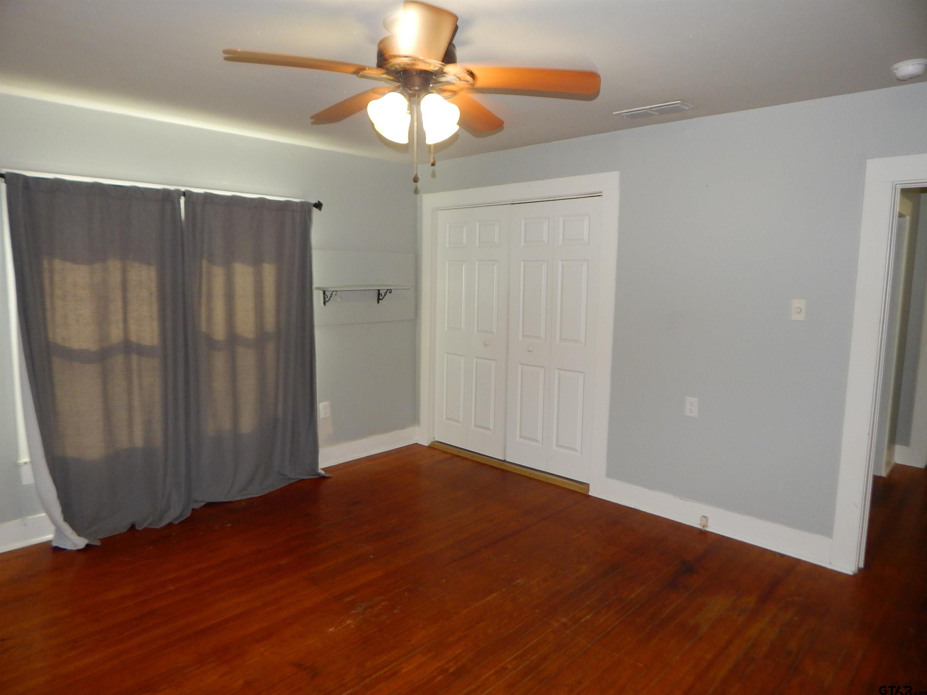 507 North Trinity Street Gilmer, TX 75644 - Photo 39 of 45 an empty room with wooden floor fan and windows