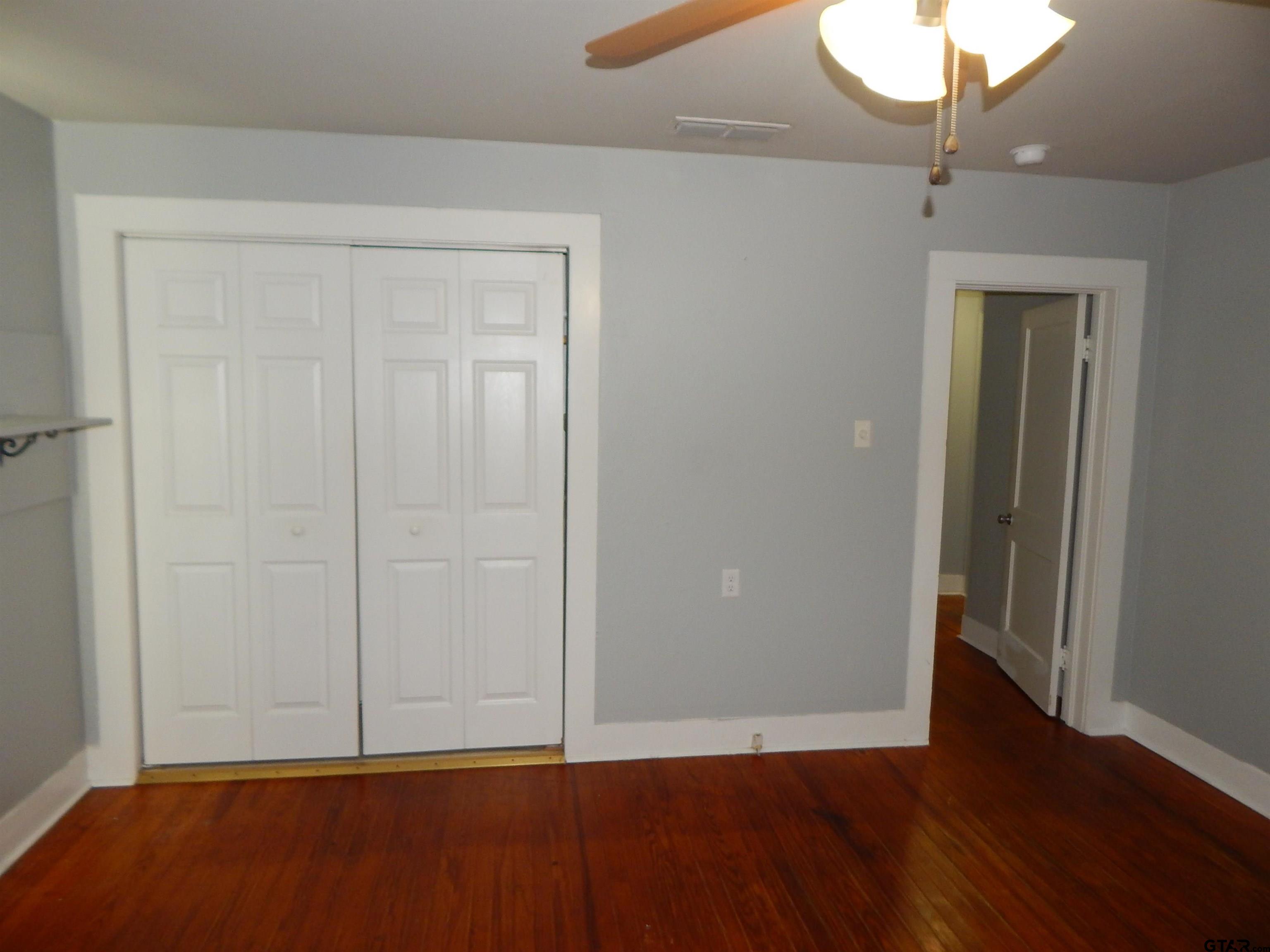 507 North Trinity Street Gilmer, TX 75644 - Photo 41 of 45 an empty room with wooden floor and fan