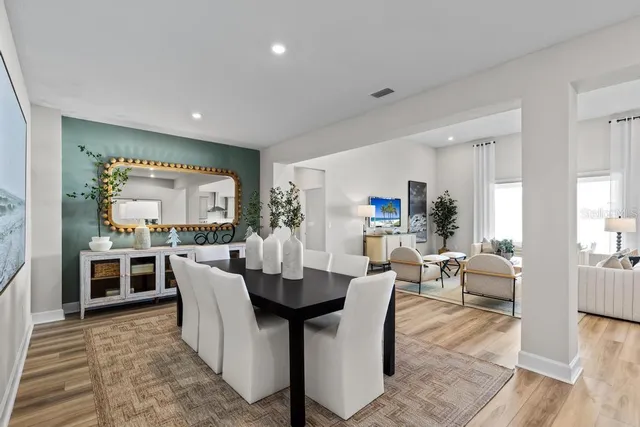 a dining room with furniture a kitchen view and wooden floor