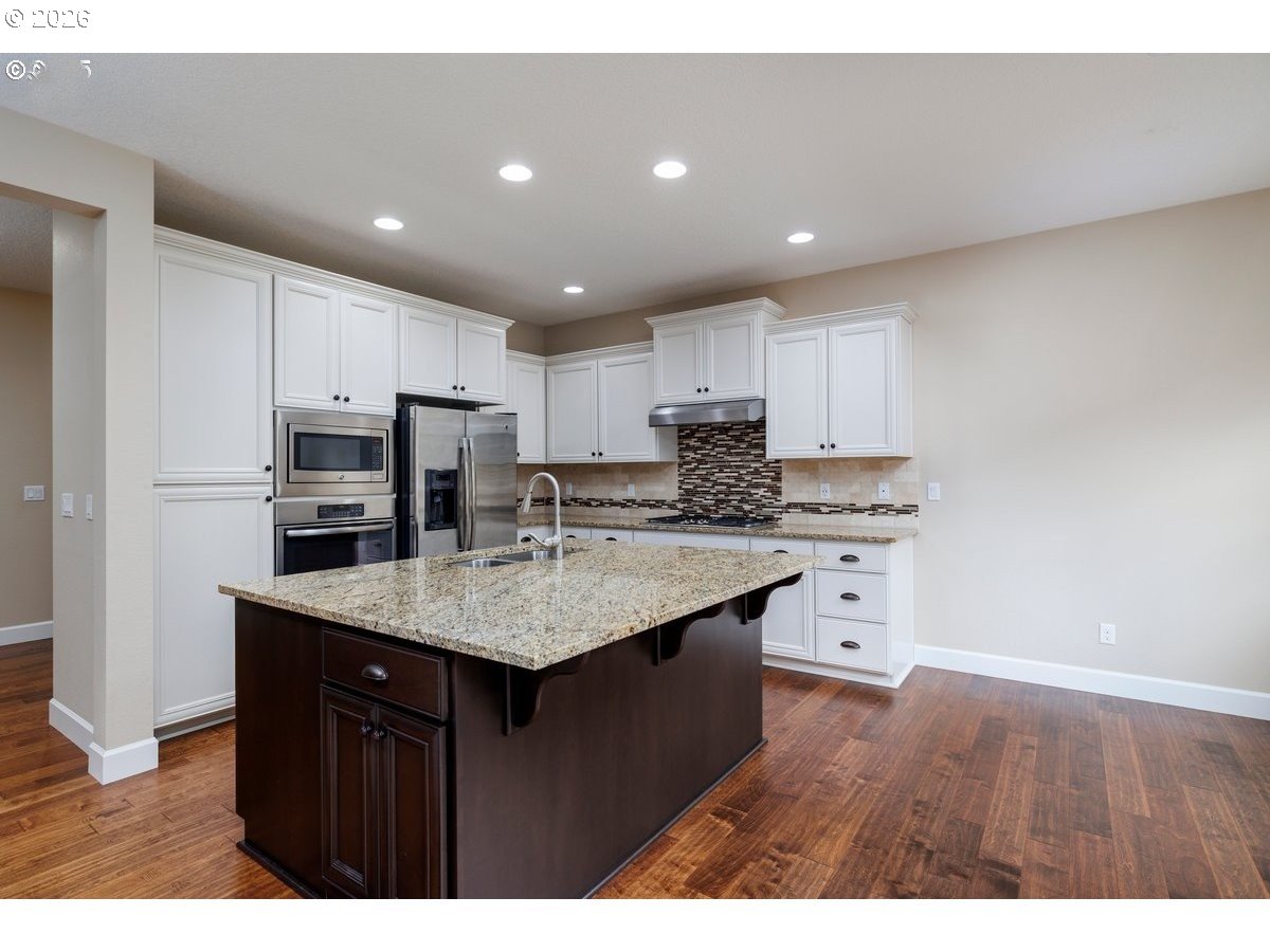 15997 Northwest Rossetta Street Portland, OR 97229 - Photo 12 of 36 a kitchen with kitchen island granite countertop a sink stove and refrigerator