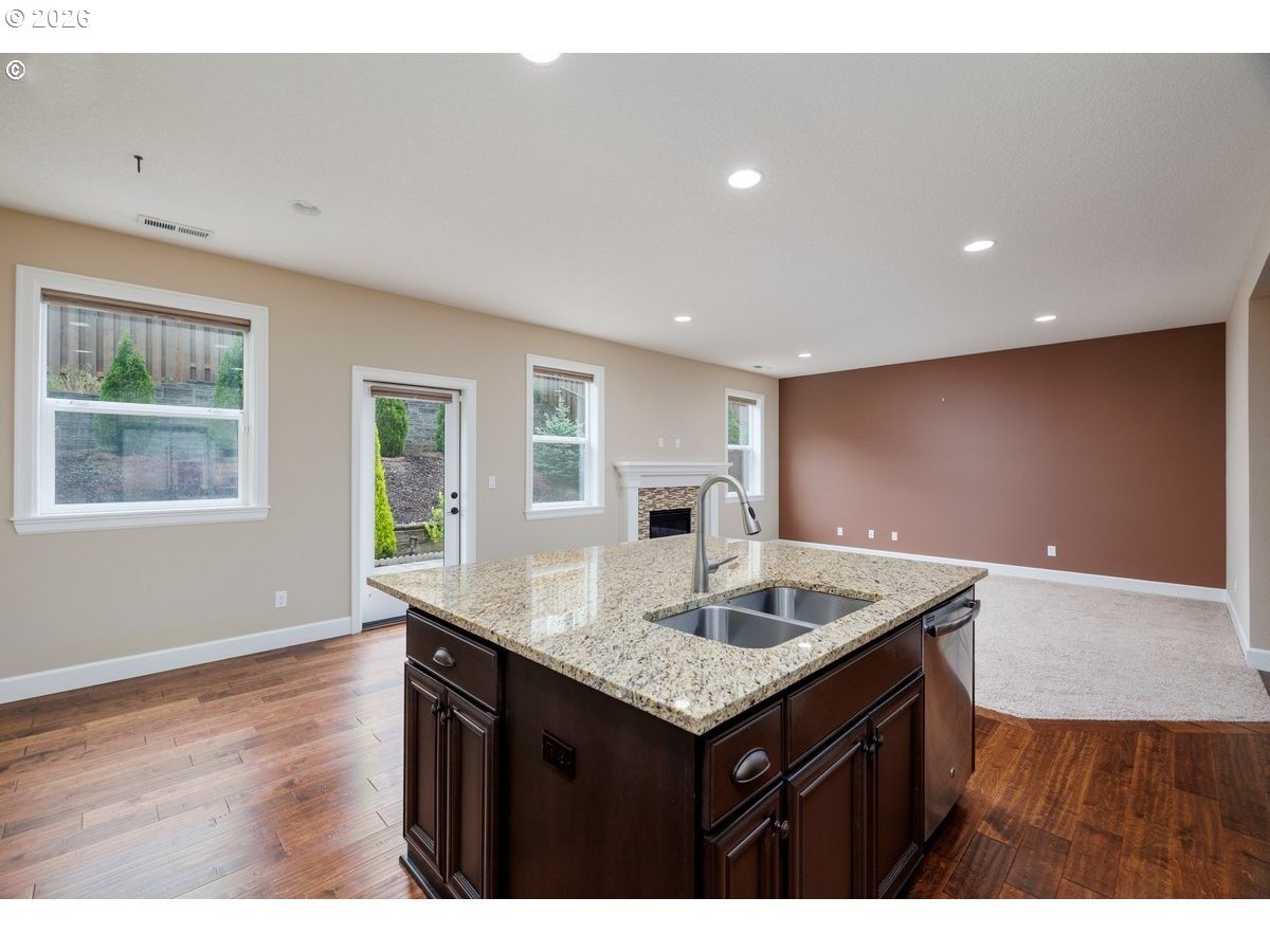 15997 Northwest Rossetta Street Portland, OR 97229 - Photo 15 of 36 a kitchen with kitchen island granite countertop a sink cabinets and wooden floor