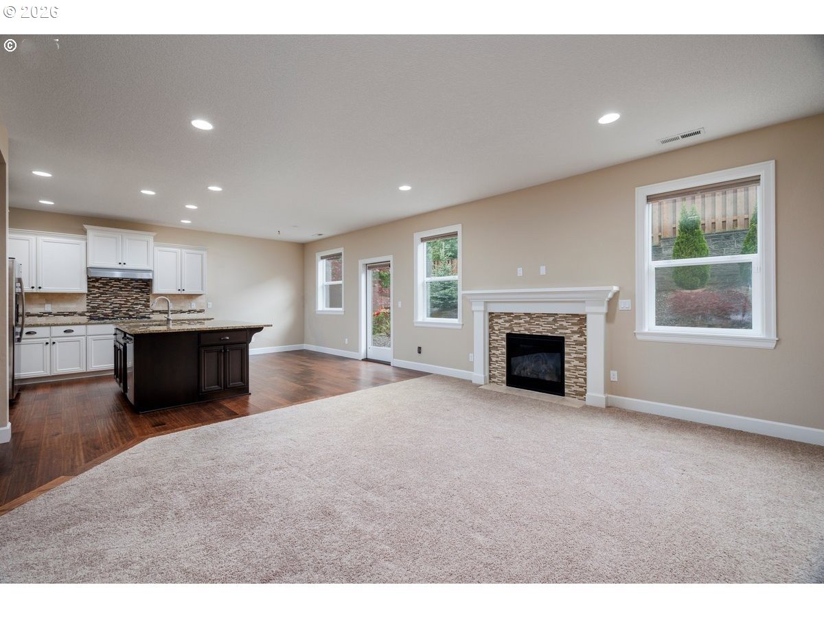 15997 Northwest Rossetta Street Portland, OR 97229 - Photo 10 of 36 a living room with stainless steel appliances kitchen island granite countertop a fireplace a flat screen tv and a fireplace