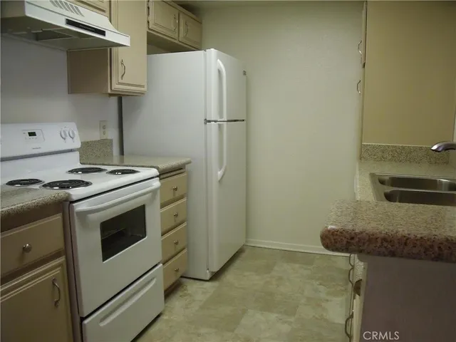 a kitchen with granite countertop a sink stove and refrigerator