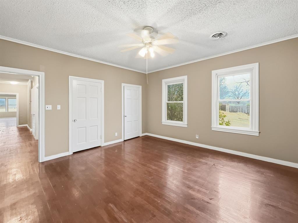 720 East Leslie Street Hamilton, TX 76531 - Photo 13 of 31 an empty room with wooden floor chandelier fan and windows