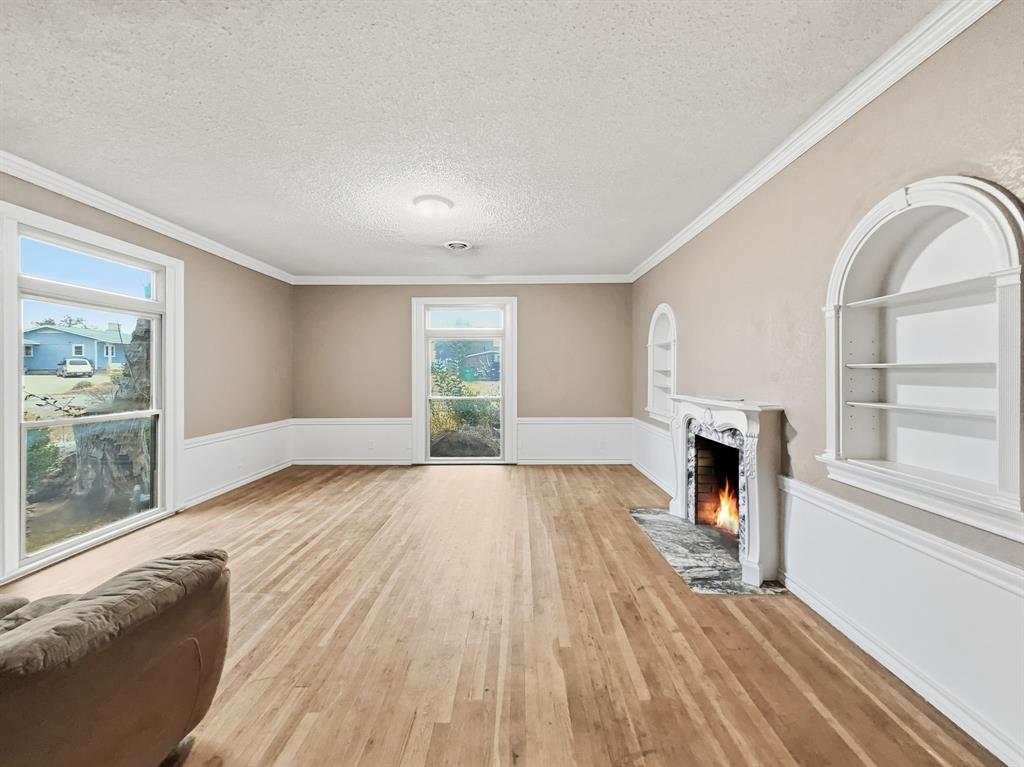 720 East Leslie Street Hamilton, TX 76531 - Photo 5 of 31 a view of empty room with wooden floor and fireplace