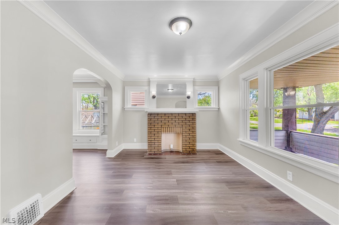 18123 McCracken Road Maple Heights, OH 44137 - Photo 5 of 27 Spacious interior featuring wood-finish flooring, a brick fireplace with mantel, crown molding, and multiple windows providing natural light