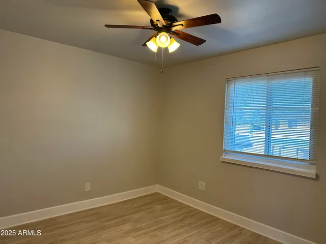 a view of an empty room with window and wooden floor