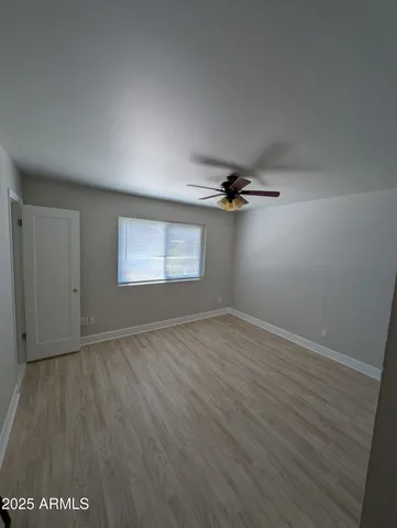 an empty room with wooden floor cabinet and windows