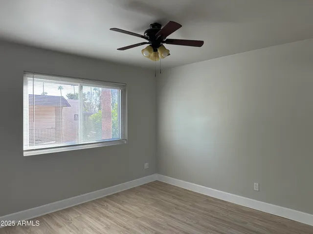 an empty room with wooden floor fan and windows