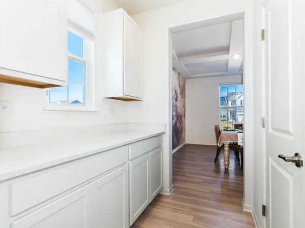 a hallway with white cabinets and wooden floor