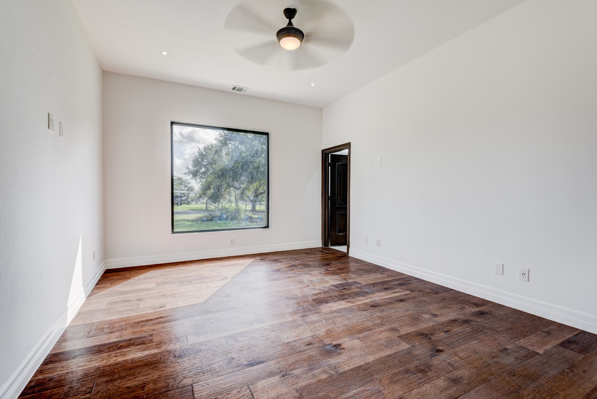 7348 Love Road Fulshear, TX 77441 - Photo 23 of 48 bright bedroom featuring rich hardwood floors, a large window with tranquil views, and a sleek ceiling fan for perfect relaxation.