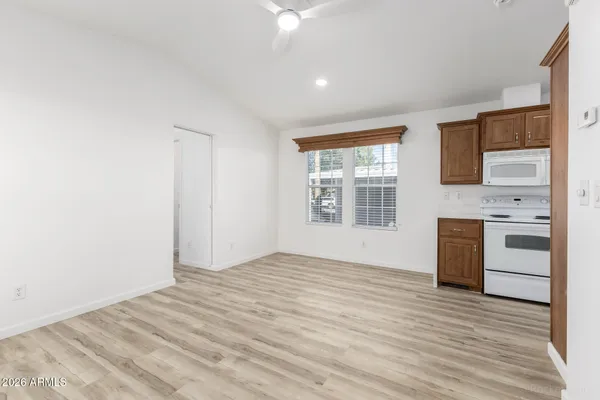 a view of an empty room with a kitchen and a window