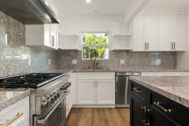 a kitchen with granite countertop a sink a stove and cabinets