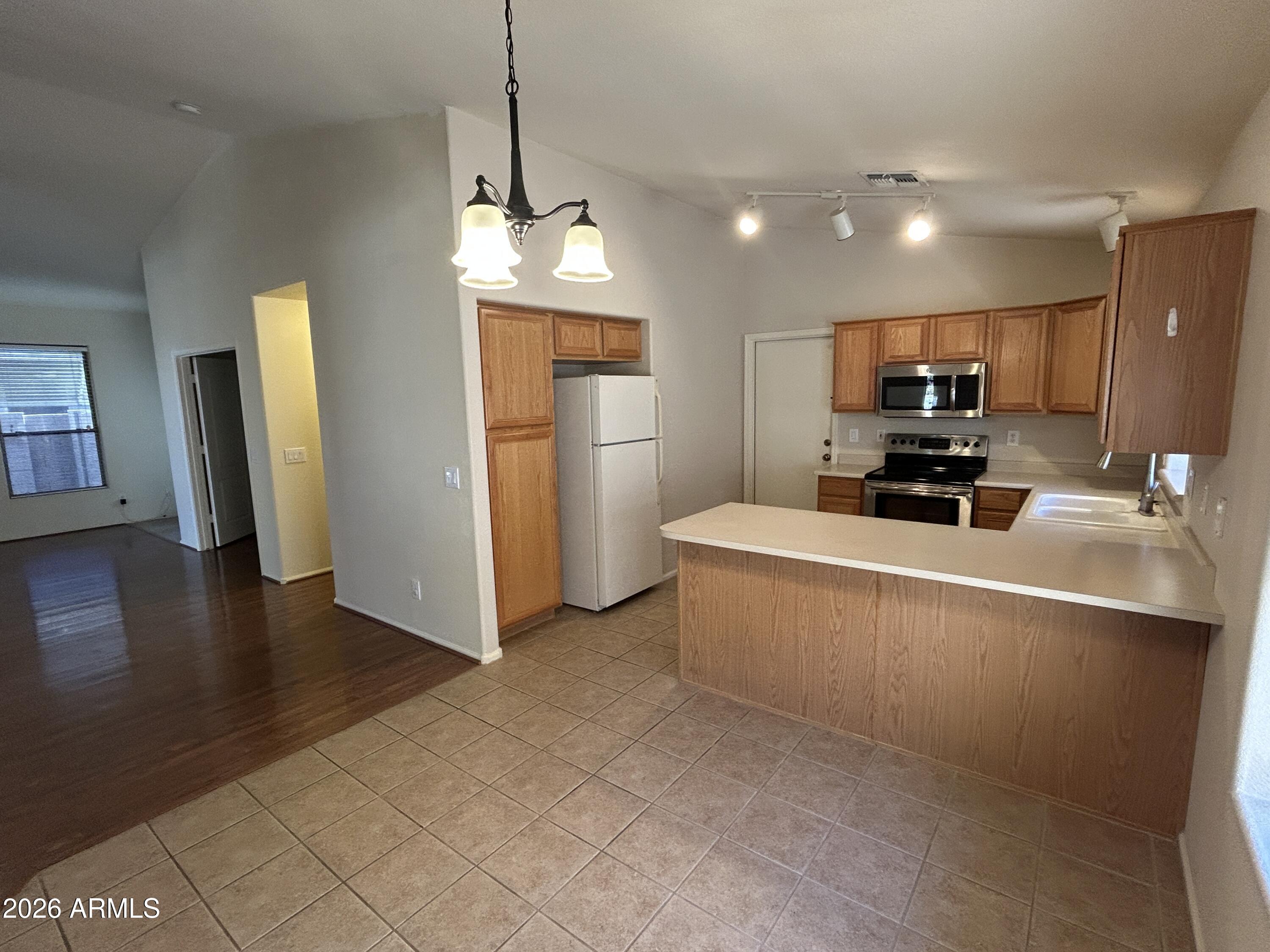 15948 West Latham Street Goodyear, AZ 85338 - Photo 3 of 14 a view of kitchen with refrigerator microwave and wooden floor