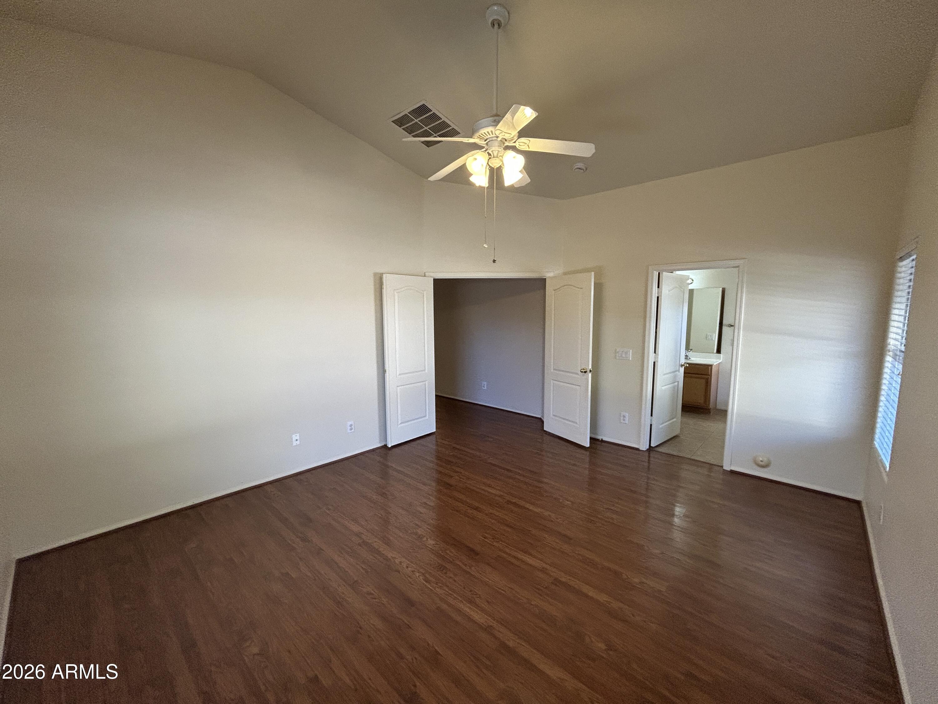 15948 West Latham Street Goodyear, AZ 85338 - Photo 7 of 14 a view of an empty room with wooden floor and a ceiling fan