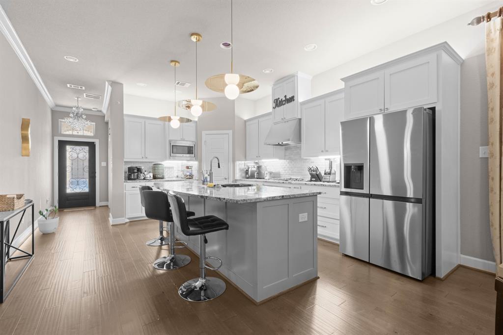 5417 Harbour Road Richardson, TX 75082 - Photo 4 of 23 a kitchen with kitchen island a refrigerator a stove a sink and a dining table with wooden floor