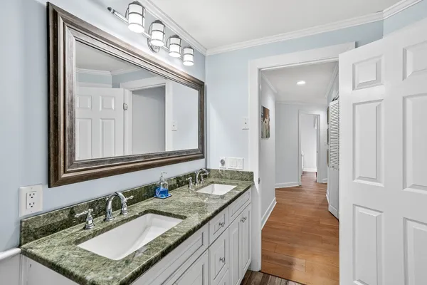 a bathroom with a granite countertop double vanity sink and a mirror