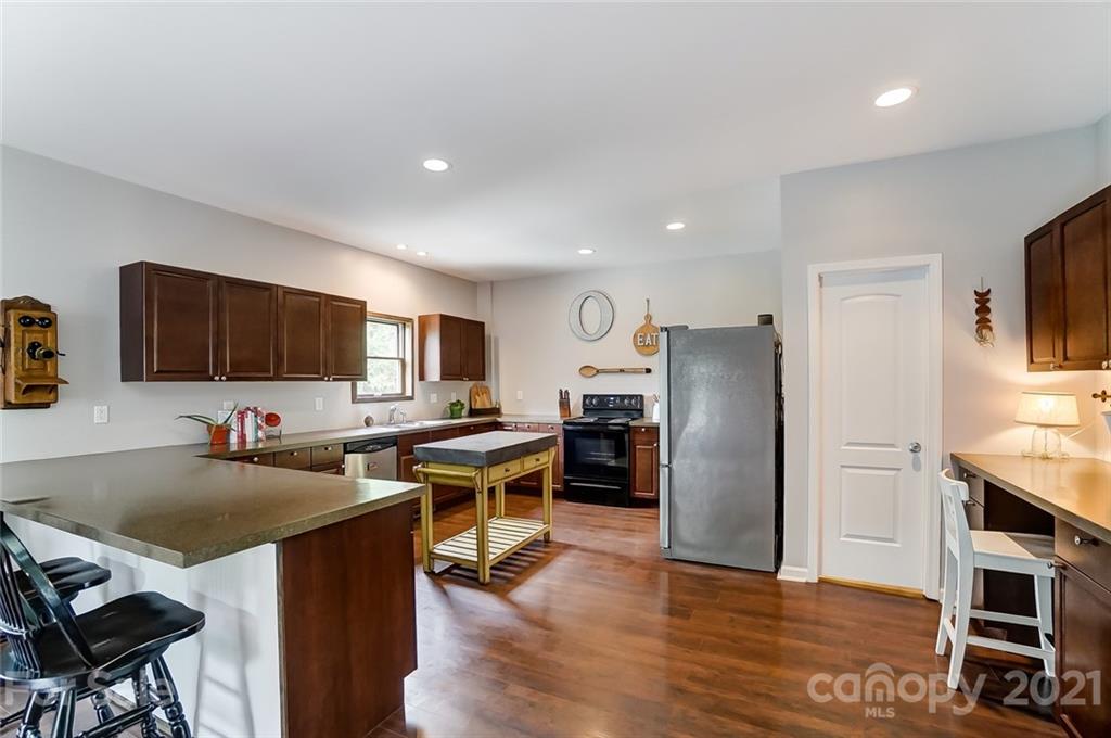 339 Lancaster Estate Road Indian Land, SC 29707 - Photo 15 of 48 a kitchen with stainless steel appliances a stove a refrigerator a sink a dining table and chairs with wooden floor