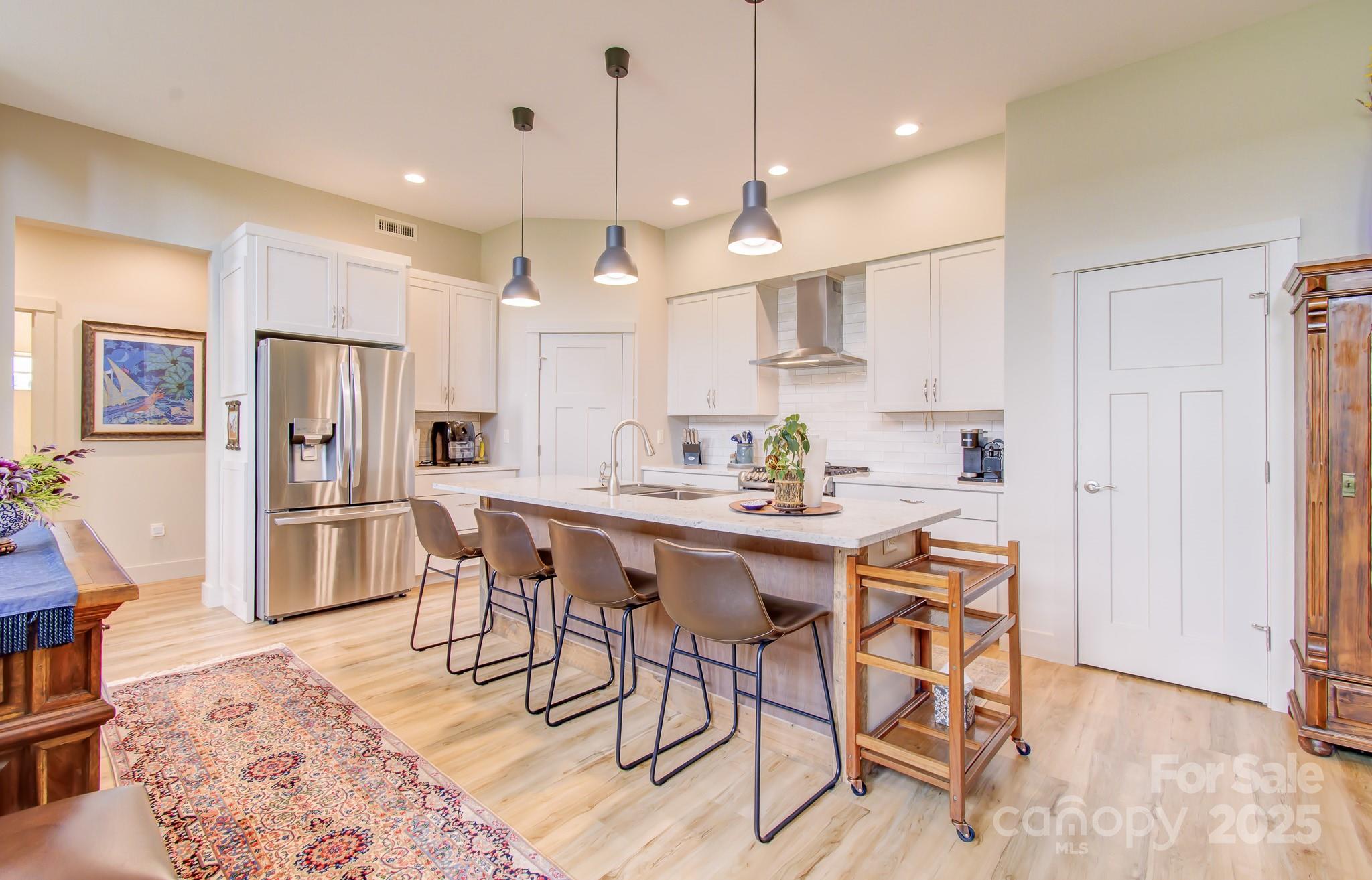 147 Majestic Ridge Road Mills River, NC 28759 - Photo 7 of 48 a kitchen with stainless steel appliances kitchen island granite countertop a refrigerator a stove a sink dishwasher and a dining table with wooden floor