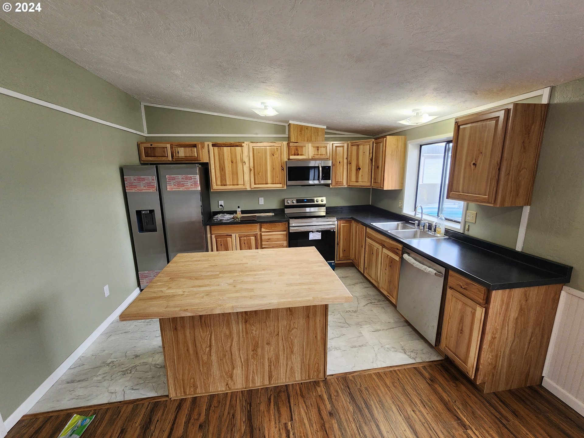 100 River Bend Road, Unit 127 Reedsport, OR 97467 - Photo 4 of 21 a large kitchen with stainless steel appliances kitchen island granite countertop wooden cabinets a refrigerator a sink a stove a microwave and island