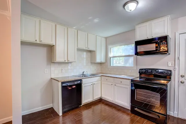a kitchen with cabinets appliances a sink and a window