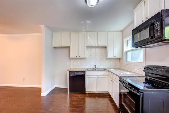 a kitchen with stainless steel appliances a sink cabinets and wooden floor