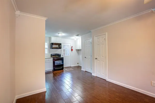 a living room with stainless steel appliances wooden floor and a window